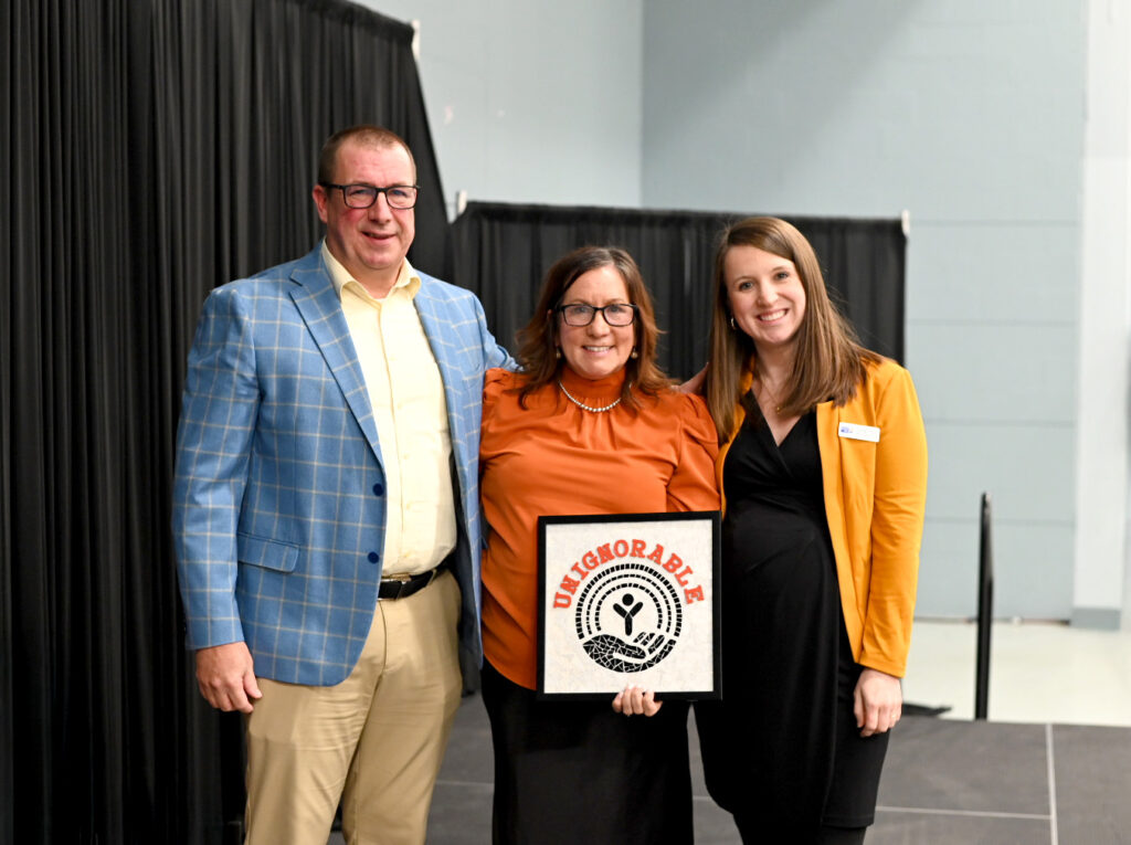 Man and two women accepting holding a mosaic of UWKV's unignorable theme and messaging